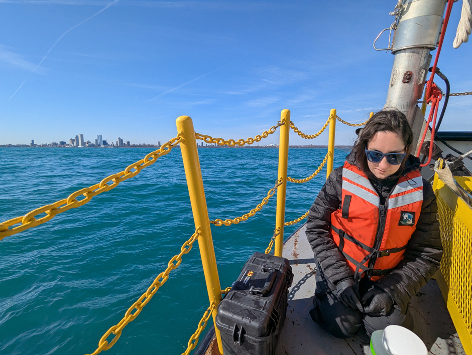 Emily Hyland supporting water collection in Lake Michigan, with Milwaukee in the background, for validation of NASA’s Plankton, Aerosol, Cloud and ocean Ecosystem (PACE) satellite sensor in March 2025.