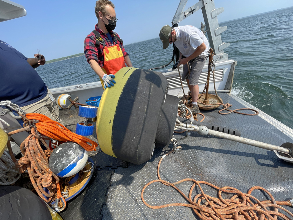 Darryl Sirleaf (NBC, left), Rich Balouskus (RIDEM Principal Marine Biologist, middle), Pat Brown (RIDEM Chafee Captain, right). Installing acoustic receiver on North Prudence Buoy in Narragansett Bay during buoy deployment (2022).