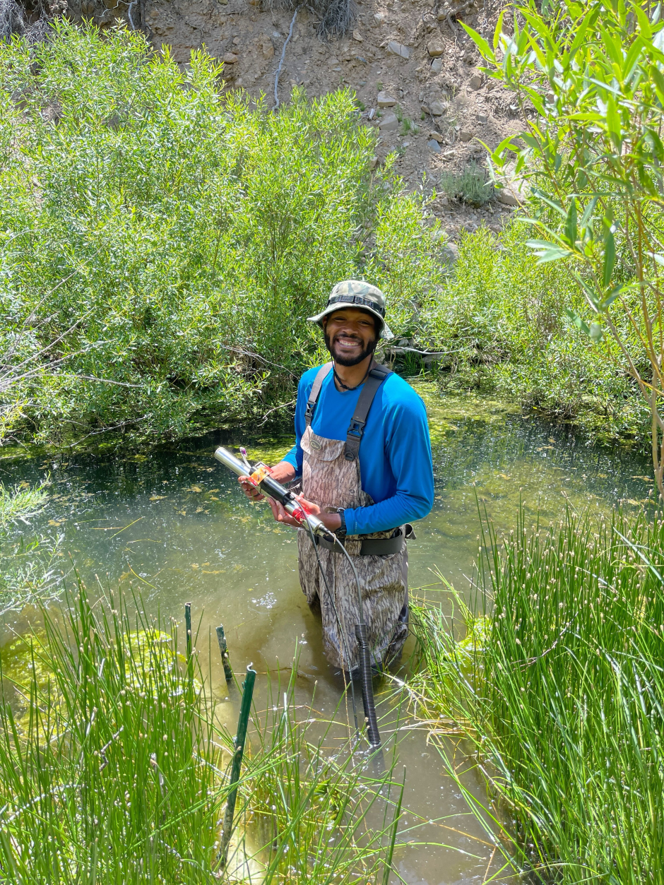 UNR graduate student Deandre Presswood holding a s::can spectrolyser in Dog Creek while ensuring it is working properly during a routine maintenance visit. 