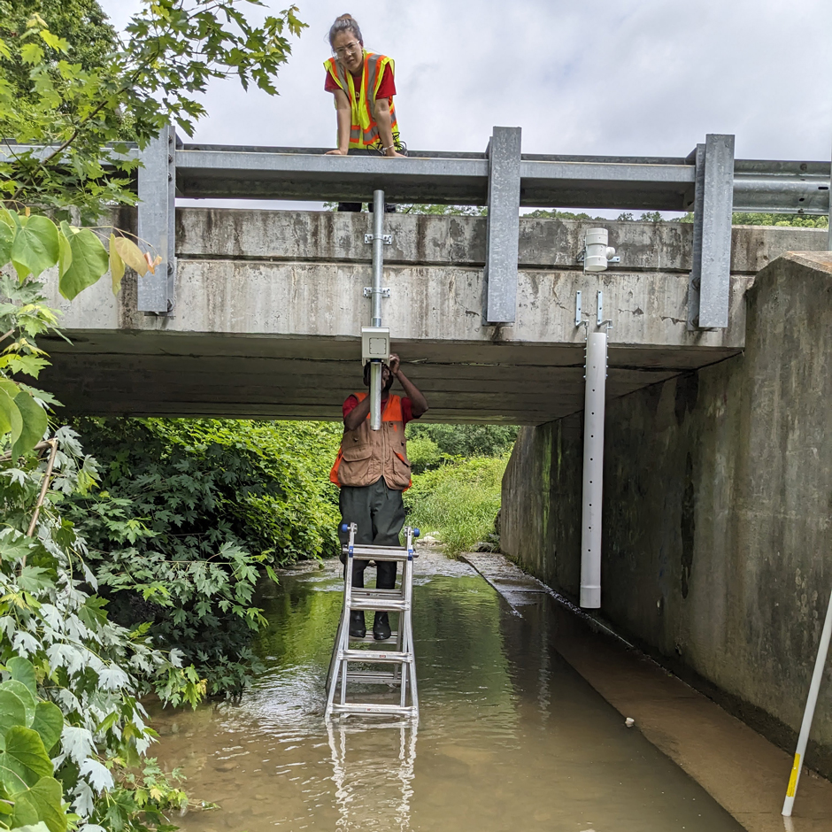 Franklin Kondum and Anju Thapa, graduate students at UofL, install Geolux noncontact flow sensor and EXO 2 sonde on Cowan Creek. The EXO 2 sonde is situated in a PVC pipe with a swinging arm to allow debris to pass and mitigate potential damage to sensors.
