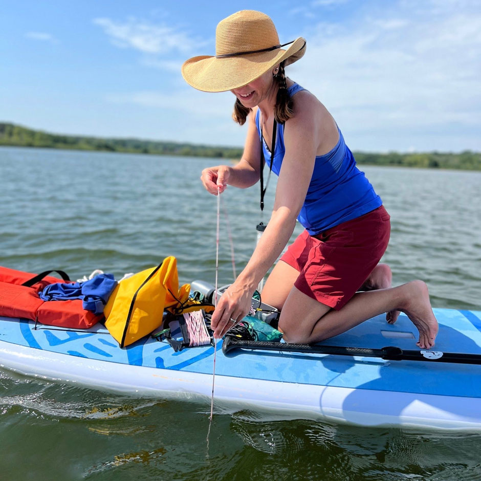 Wisconsin Citizen Lake Monitoring Network volunteer Lisa Grueneberg lowers a Secchi disc from her paddleboard on Lake Wingra near Madison, Wisconsin.