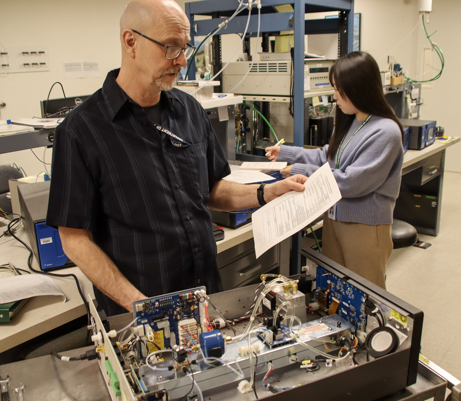 Davis's colleagues, John Wolbert and Qianna Xu, performing seasonal maintenance on an ozone monitor.