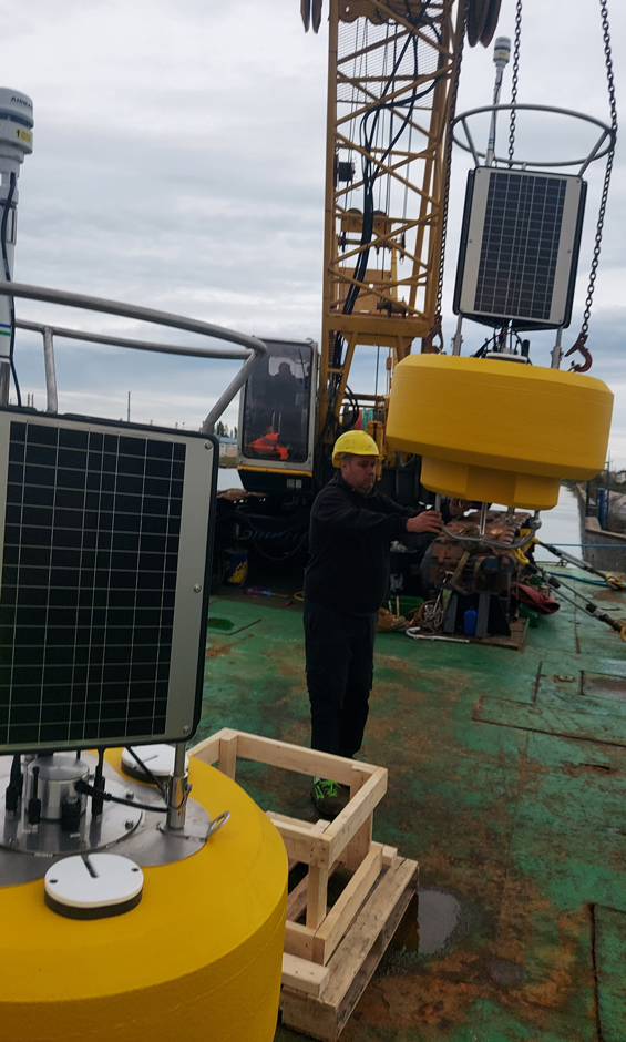 The buoys are loaded onto the barge in preparation for deployment.