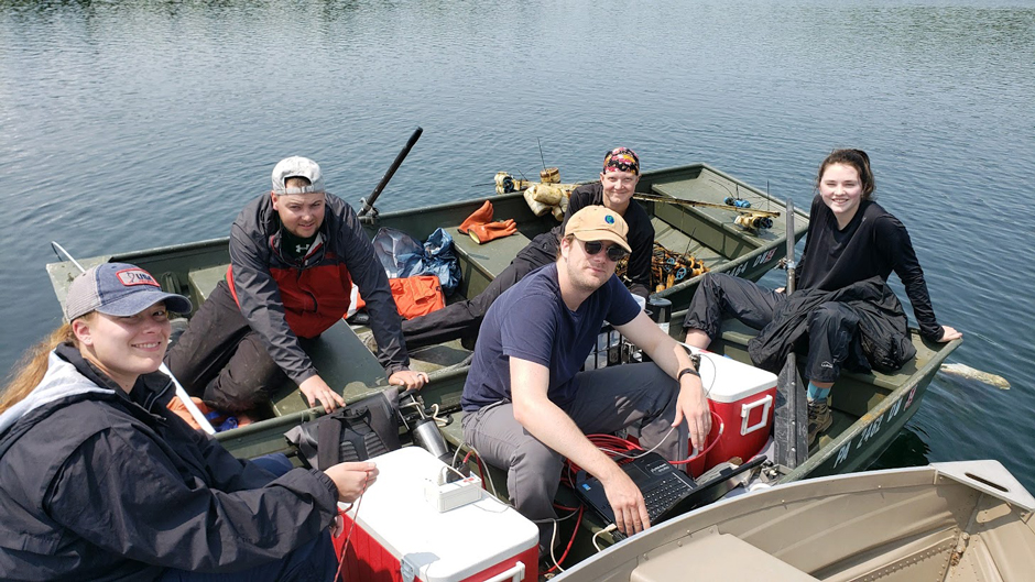 A group of RPI undergraduate students, graduate students, and a professor/researcher from RPI on Lake Giles with a recently retrieved sensor line and coolers filled with water samples and sampling equipment.