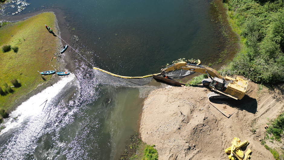 The construction crew places a block net and turbidity curtain to protect water quality and keep aquatic species out of a gravel pit prior to restoration.